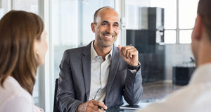 Consultant in suit looking at clients and smiling.