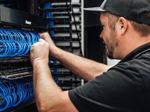 Low voltage electrician installing cables in a server room.