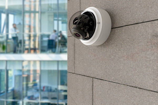 Security camera mounted on a building wall with an office interior in the background